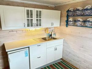 una cocina con armarios blancos y fregadero en Three-Bedroom Holiday home in Åkra en Kyrping