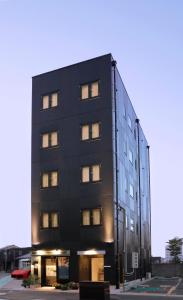 een zwart gebouw met veel ramen in een straat bij precious days inn in Fukuoka
