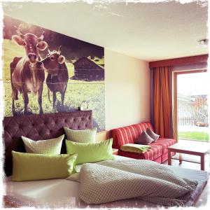 a bedroom with a painting of two cows on the wall at Hotel Garni Alpendiamant in Fiss