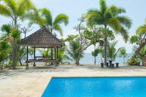 a resort with a pool and a gazebo at RedDoorz at Tanjung Alam Hotel Lovina in Buleleng