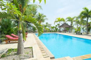 a swimming pool with a palm tree and a gazebo at RedDoorz at Tanjung Alam Hotel Lovina in Buleleng