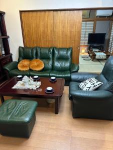 sala de estar con sofá de cuero verde y mesa en season guest house, en Tokio