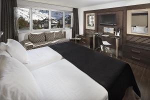 a bedroom with a large white bed and a couch at Meliá Sol y Nieve in Sierra Nevada