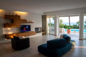 ein Wohnzimmer mit einem TV, einem blauen Sofa und einem TV in der Unterkunft Villa White Dahlia in Torre Suda