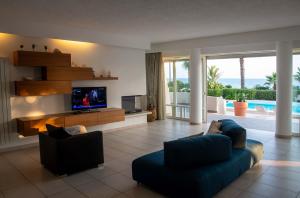 Una sala de estar con un televisor y un sofá azul y un televisor. en Villa White Dahlia, en Torre Suda