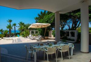 Una mesa con sillas y una sombrilla en un patio. en Villa White Dahlia, en Torre Suda