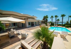 ein Haus mit einem Pool mit Stühlen und einem Sonnenschirm in der Unterkunft Villa White Dahlia in Torre Suda