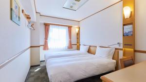 a hotel room with two beds and a table at Toyoko Inn Tokyo Nihombashi Ningyocho in Tokyo