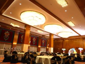 um salão de banquetes com mesas, cadeiras e lustres em Shyama Sarovar Portico em Orai