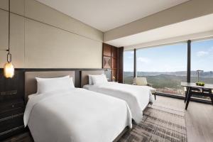 two beds in a hotel room with a view at Shangri-La Nanning - The tallest hotel worldwide in Shangri-La Group in Nanning