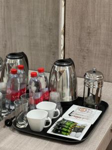 a tray with coffee pots and cups on a table at Diyora Hostel in Qŭyliq