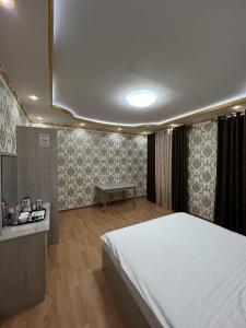 a bedroom with a large white bed and a table at Diyora Hostel in Qŭyliq
