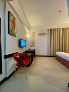 Habitación con silla roja, cama y escritorio. en My Inn Hotel Lahad Datu, Sabah, en Lahad Datu
