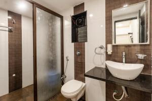 ein Badezimmer mit einem Waschbecken, einem WC und einem Spiegel in der Unterkunft Hotel Vyankatesh & Pure Veg Restaurant in Mahabaleshwar