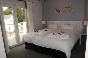 a bedroom with a large white bed with red roses on it at Quay West in Velddrif