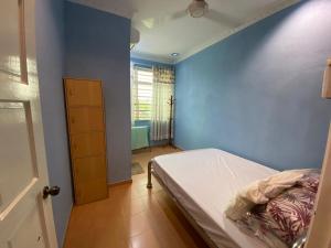 1 dormitorio con cama y pared azul en Homestay LA Kota Bharu, en Kota Bharu