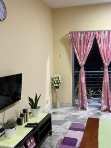 uma sala de estar com cortinas cor-de-rosa e uma janela em PD VIP Pool View w WiFi - Anugerah Staycation em Porto Dickson