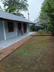 uma casa com um jardim de relva ao lado de um edifício em ชิดชล โฮมสเตย์ แอทอัมพวา em Bang Khon Thi