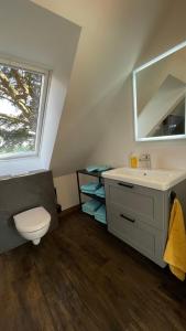 ein Bad mit einem Waschbecken, einem WC und einem Fenster in der Unterkunft Meine Schule Sehlingen, stilvolle Familien-Unterkunft auf dem Land in Kirchlinteln