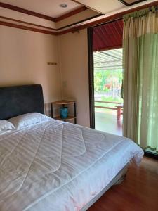 um quarto com uma cama grande e uma porta de vidro deslizante em ชิดชล โฮมสเตย์ แอทอัมพวา em Bang Khon Thi