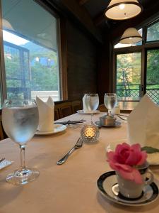 a table with wine glasses and a flower on it at Pension Puutaro in Zao Onsen