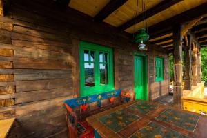 a porch of a log cabin with a table and green windows at La sat - Mândră Ioană in Bertea