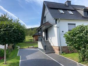 a white house with a black roof and a driveway at Balance Apartments by M&A - Ferienwohnung Dohrenbach in Witzenhausen