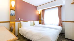 a hotel room with two beds and a window at Toyoko Inn JR Yokohama sen Sagamihara Ekimae in Sagamihara
