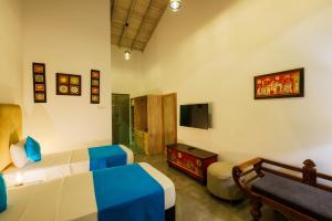 a bedroom with a bed and a couch and a tv at Angam Villas Colombo in Colombo