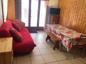 uma sala de estar com um sofá vermelho e uma mesa em Chalets La Caillaude em La Salle Les Alpes