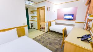 a room with two beds and a desk with a phone at Toyoko Inn Yokohama Tsurumi eki Higashi guchi in Yokohama