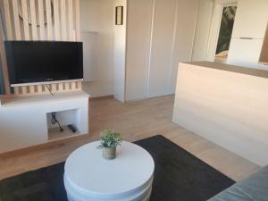 sala de estar con mesa blanca y TV en Le Château des Abeilles - appartement récemment rénové - proche centre village et route des vins, en Scherwiller