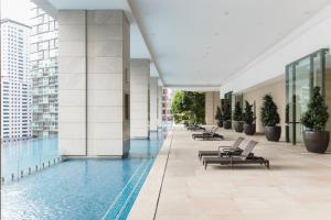 a building with a swimming pool and lounge chairs at Banyan Signatures Pavilion Kuala Lumpur by Opus Hospitality in Kuala Lumpur