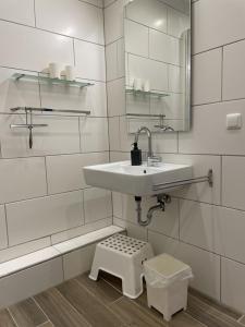 a white bathroom with a sink and a stool at Ferienwohnung Lavendel in Butjadingen