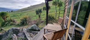 two chairs on a porch with a view of a mountain at Manaaki Mai, Rustic Retreat Bush Cabin in Christchurch