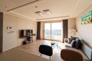 uma sala de estar com um sofá e uma televisão em Hotel The Blue Terra em Sokcho