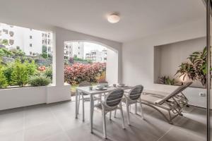 a dining room with a table and chairs and a window at Jardines - Tabor 0-2 POOL VIEW & GARDEN 1B in Palm-mar