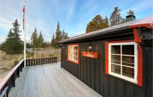 een zwart gebouw met een bord op een houten terras bij 3 Bedroom Stunning Home In Sjusjen in Sjusjøen