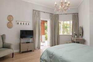 1 dormitorio con 1 cama, TV y silla en Isoyi On The Mill en Durban