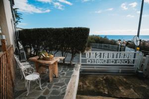 un patio con tavolo, sedie e vista sull'oceano di Agriturismo Rose di Pietra a Pietra Ligure
