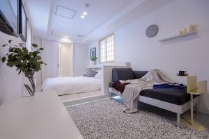 a white room with a bed and a couch at Asakusa Designer Hotel YOSHII in Tokyo