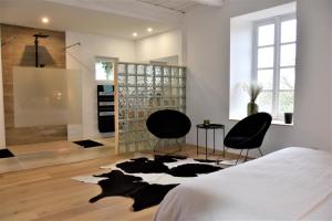 sypialnia z 2 krzesłami i łóżkiem w pokoju w obiekcie Domaine du Conte Bleu w mieście Sainte-Gemme