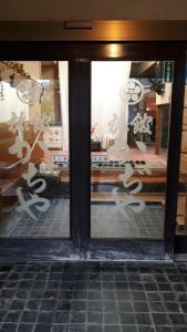 Uma porta de vidro com letras asiáticas. em Kajiyabekkan Ramakkoro Yamaneko Yado em Ichinoseki