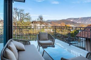 a patio with a couch and chairs on a balcony at Eichhof Apartment Lavendel in Termeno
