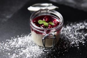 a dessert in a glass jar on a table with powdered sugar at Haubers Naturresort in Oberstaufen