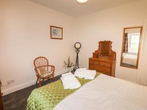 a bedroom with a bed and a chair and a mirror at Millerbeck in Ambleside