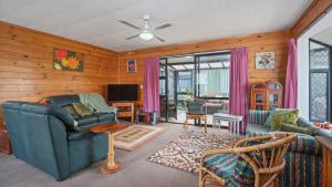 ein Wohnzimmer mit einem Sofa und einem TV in der Unterkunft Roseville - Snells Beach Holiday Home in Snells Beach
