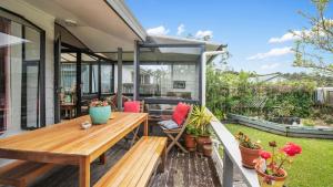 eine Außenterrasse mit einem Holztisch und Bänken in der Unterkunft Roseville - Snells Beach Holiday Home in Snells Beach