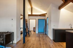 cocina abierta y sala de estar con paredes blancas y suelo de madera. en Eichhof Apartment Wacholder en Termeno