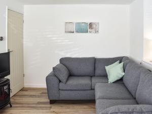 ein Wohnzimmer mit einem grauen Sofa und einem TV in der Unterkunft Old Chapel in Levens